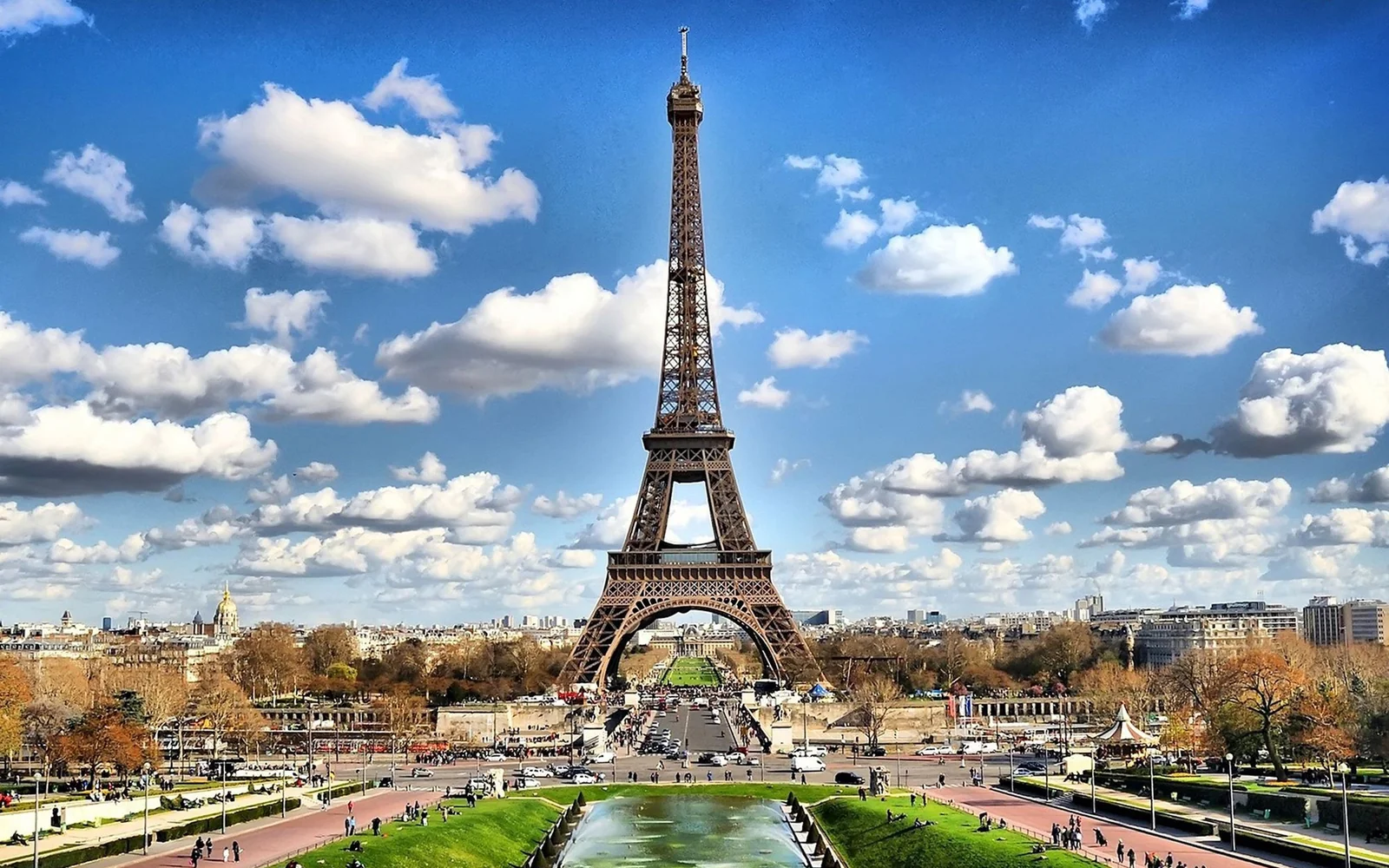 The Eiffel Tower rising above Paris beneath a cloudy daytime sky.