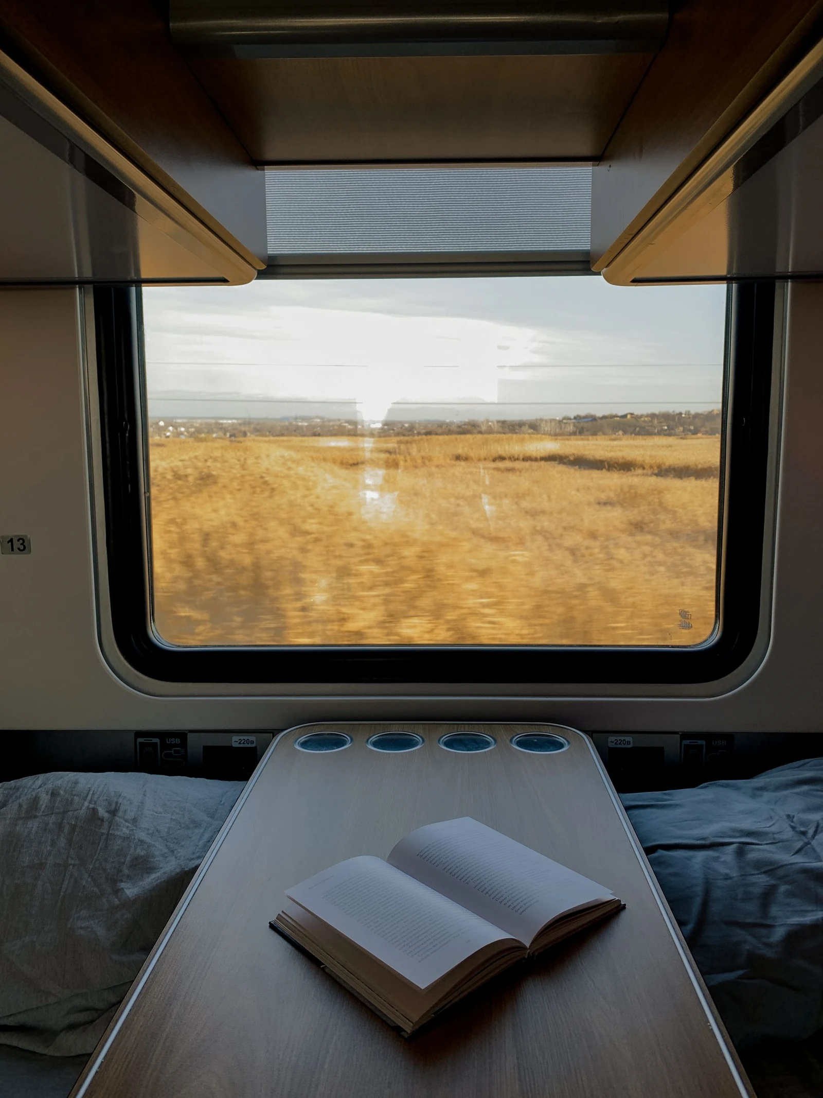 A train table beside a window with a view of the countryside