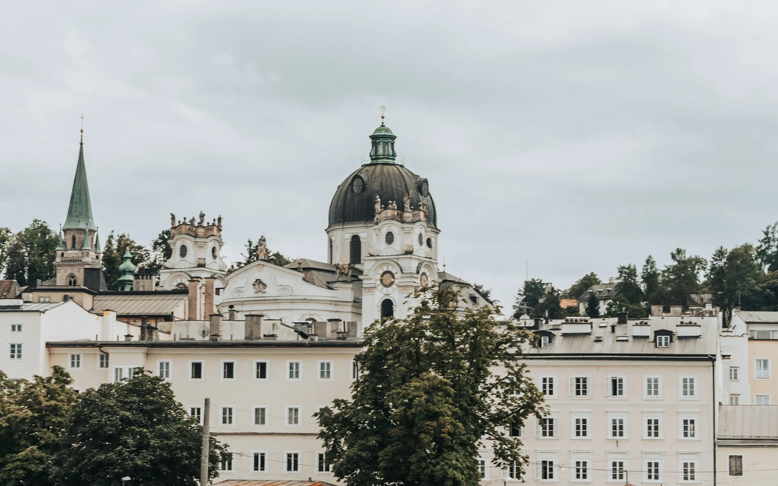 Historic Salzburg buildings and domes beside the Salzach River.