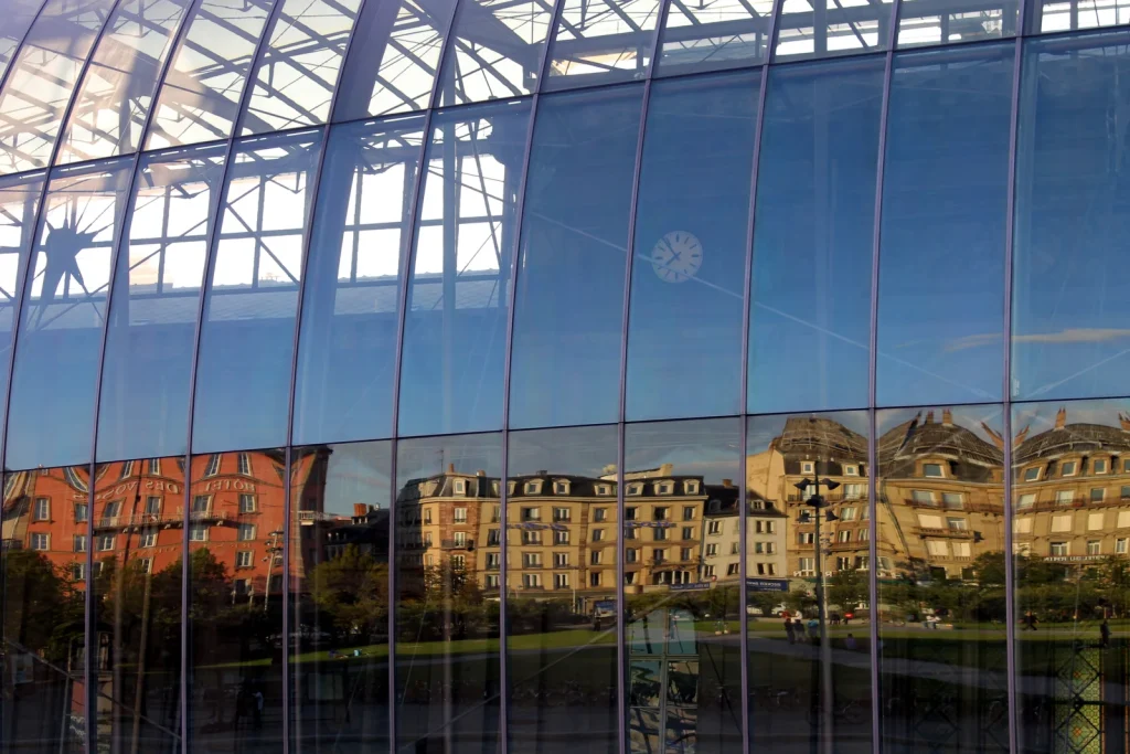 Curved glass fa&ccedil;ade of Strasbourg railway station reflecting buildings on Place de la Gare.