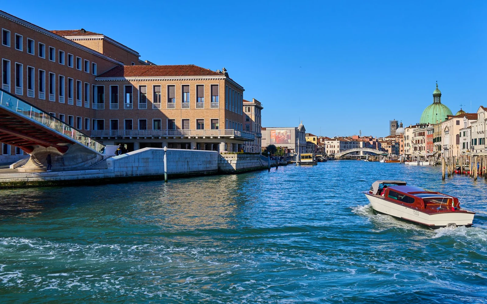 A daytime view along Venice's Grand Canal with boats and historic waterfront buildings.